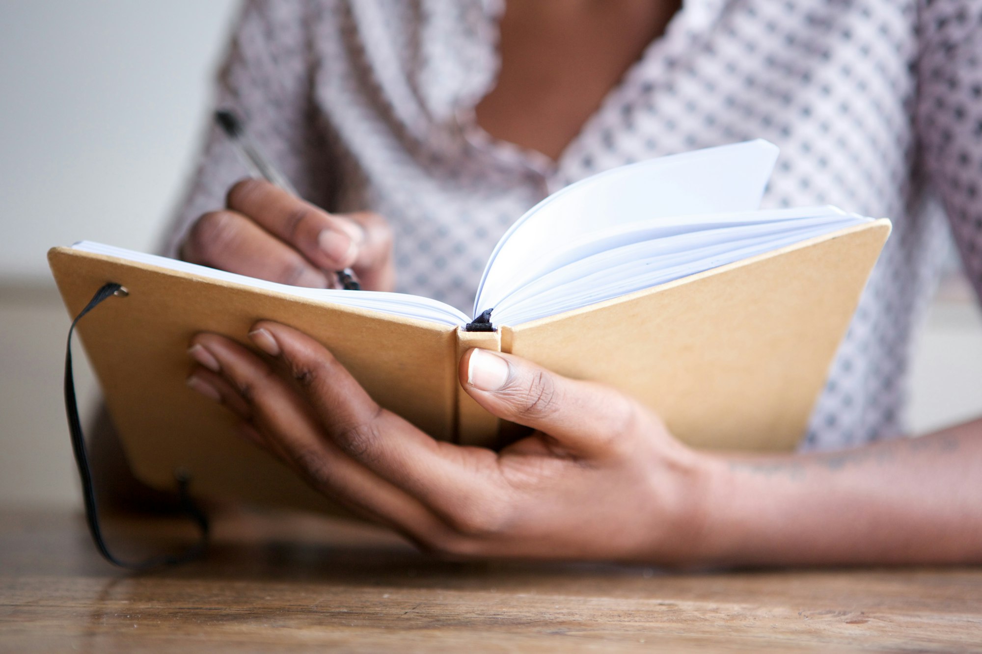 Partial portrait of black female author at home writing in journal Partial portrait of black female author at home writing in journal